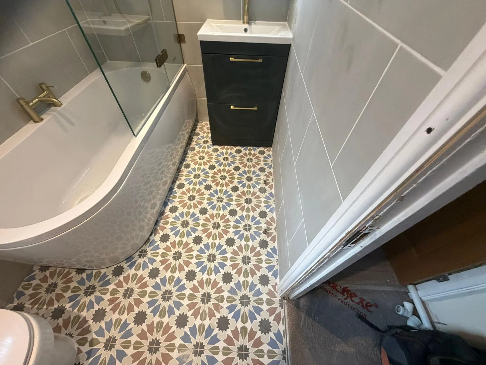 Patterned bathroom floor beside a dark vanity and curved bath — RV Renovation, Oxford