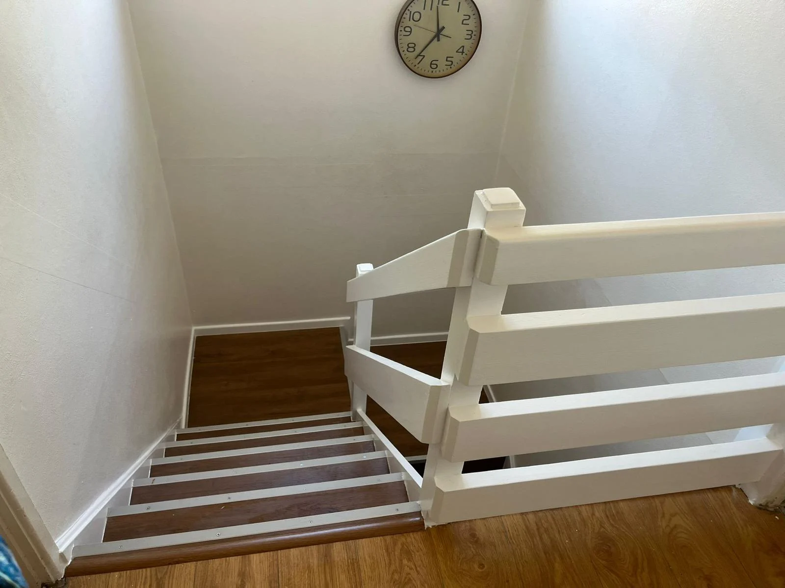 Wood-effect landing and stair covering beside a white balustrade — RV Renovation, Oxford