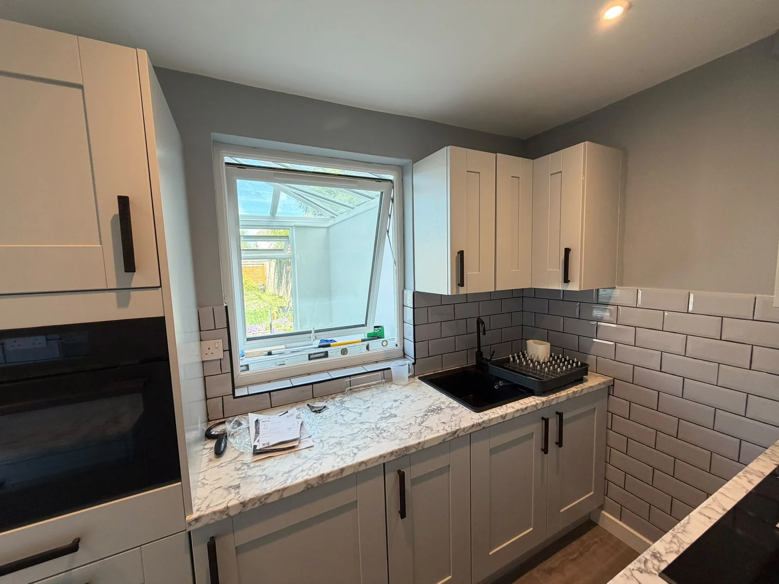 Kitchen sink below a window with corner worktop and oven — RV Renovation, Oxford