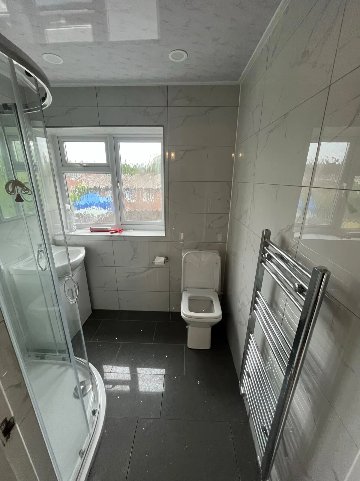 Glass corner shower, black tiled floor and chrome towel rail — RV Renovation, Oxford